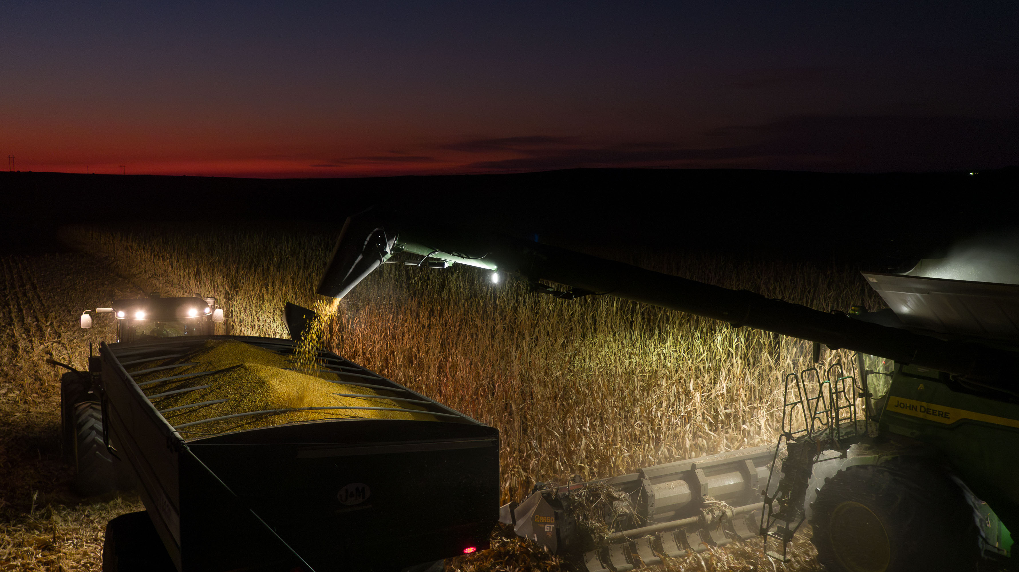John Deere Tractor with Combine at night during harvest